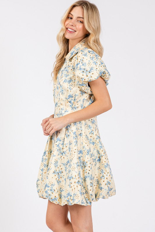 Floral eyelet mini dress with puff sleeves and a zipper front closure, designed for a chic and feminine look.