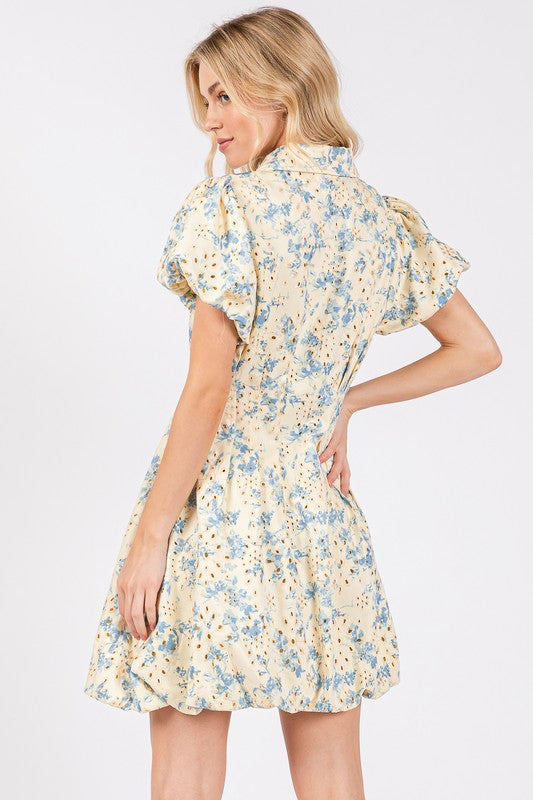 Floral eyelet mini dress with puff sleeves and a zipper front closure, designed for a chic and feminine look.