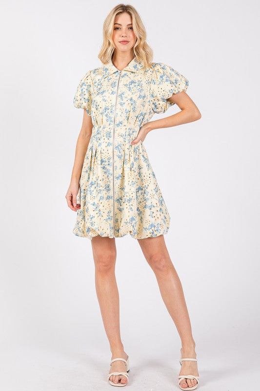 Floral eyelet mini dress with puff sleeves and a zipper front closure, designed for a chic and feminine look.