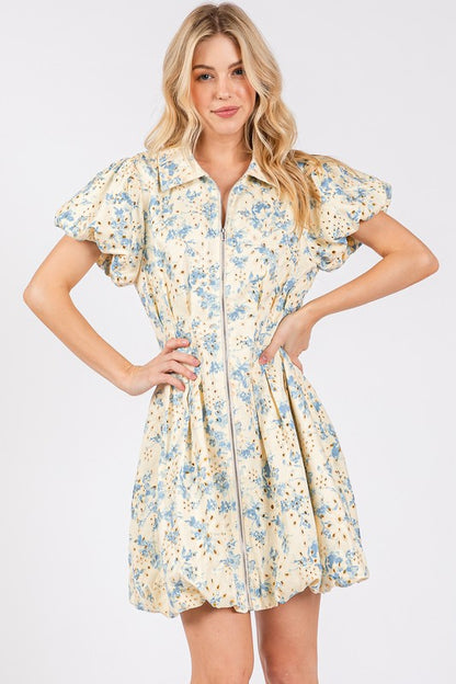 Floral eyelet mini dress with puff sleeves and a zipper front closure, designed for a chic and feminine look.