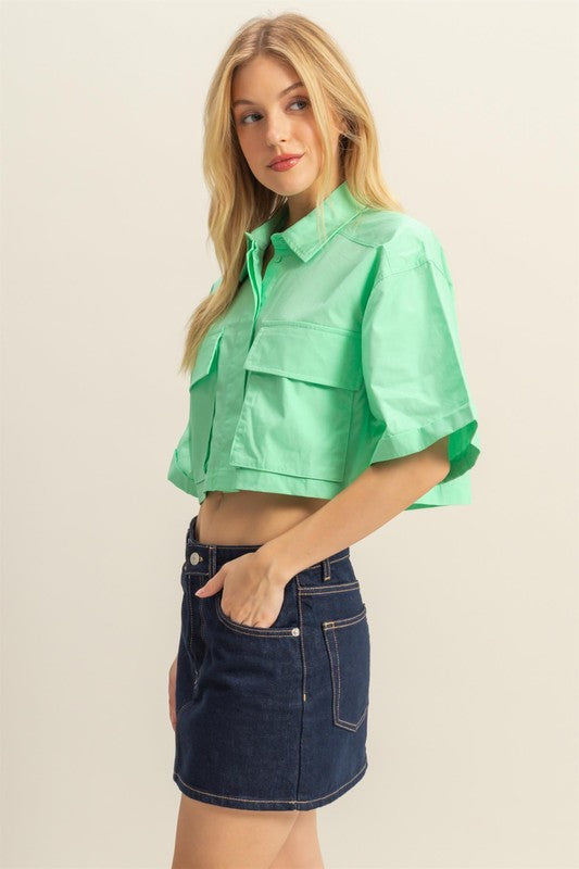 Trendy poplin collared crop shirt with front pockets, featuring a modern and structured design.