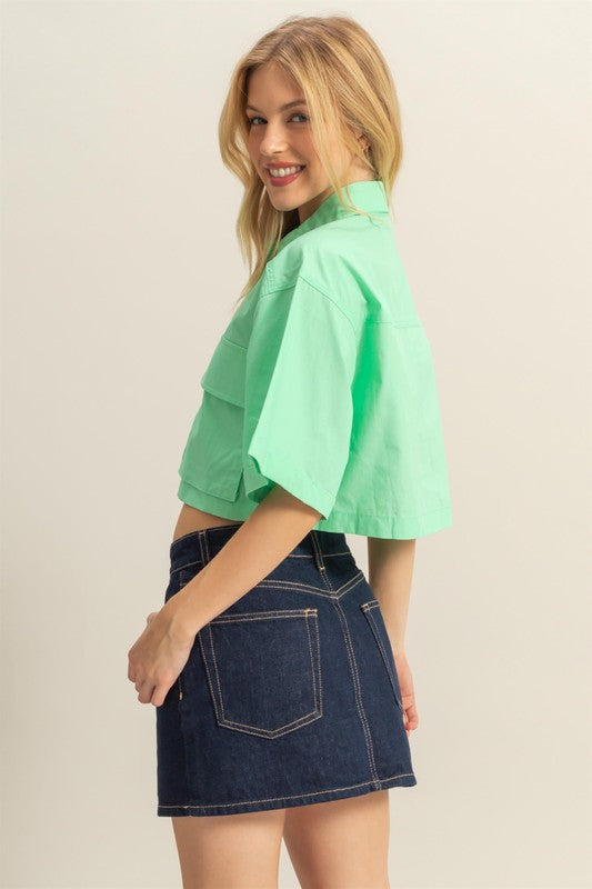 Trendy poplin collared crop shirt with front pockets, featuring a modern and structured design.