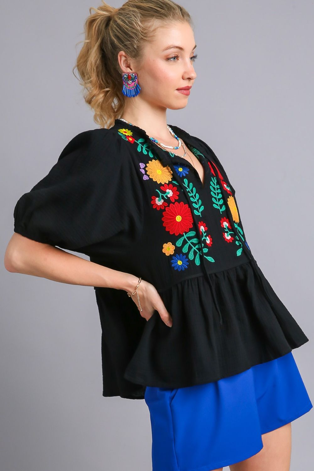 Feminine cotton gauze babydoll blouse with floral embroidery and a flattering peplum hem, perfect for a romantic bohemian look.