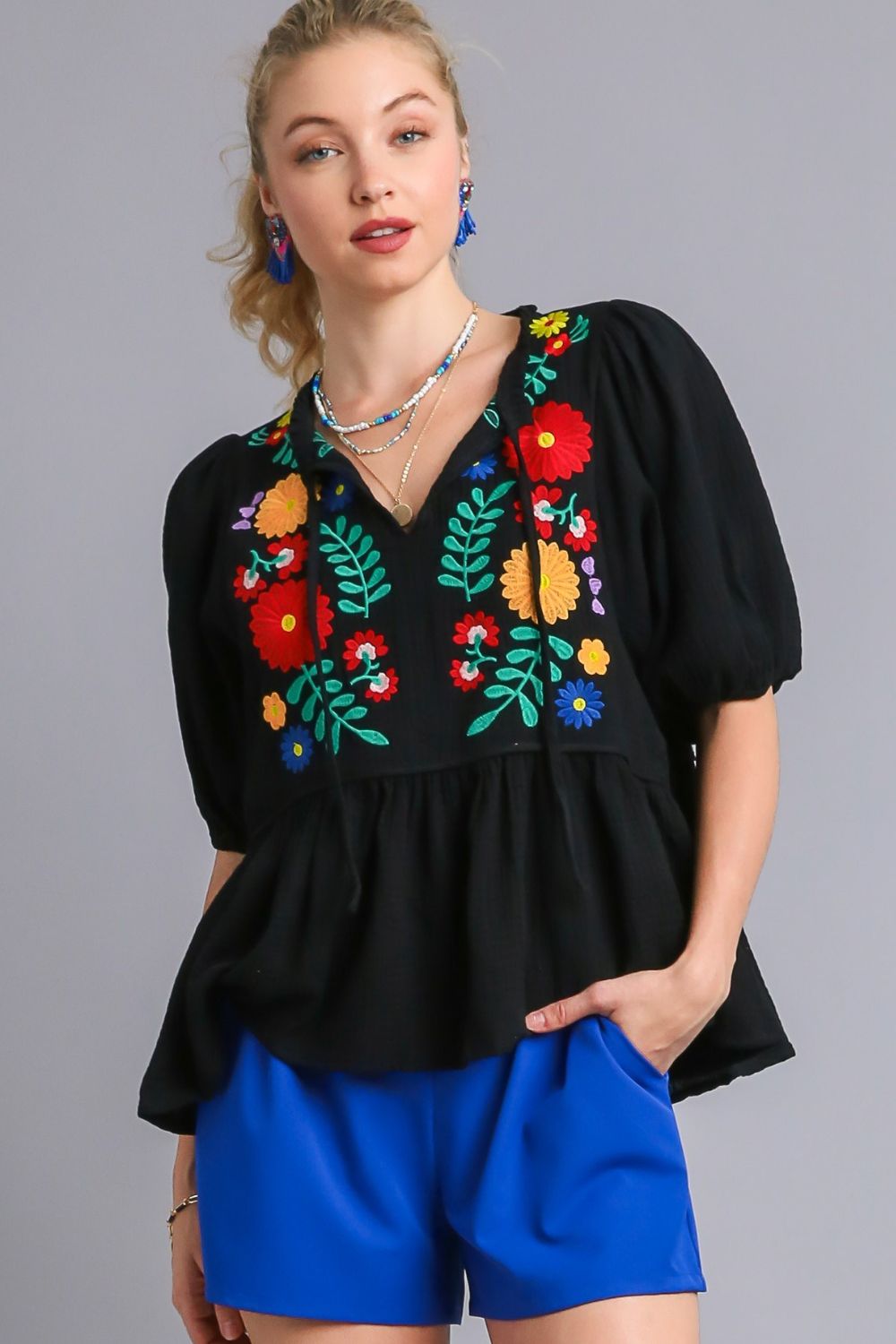 Feminine cotton gauze babydoll blouse with floral embroidery and a flattering peplum hem, perfect for a romantic bohemian look.