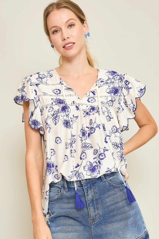 Floral print blouse with tassel tie neckline and scalloped sleeves, perfect for a breezy, boho-inspired plus-size look.