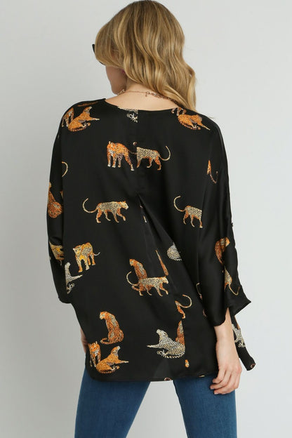 Bold high-low satin blouse with an animal print design and V-neckline, perfect for a chic and stylish look.