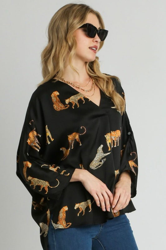 Bold high-low satin blouse with an animal print design and V-neckline, perfect for a chic and stylish look.