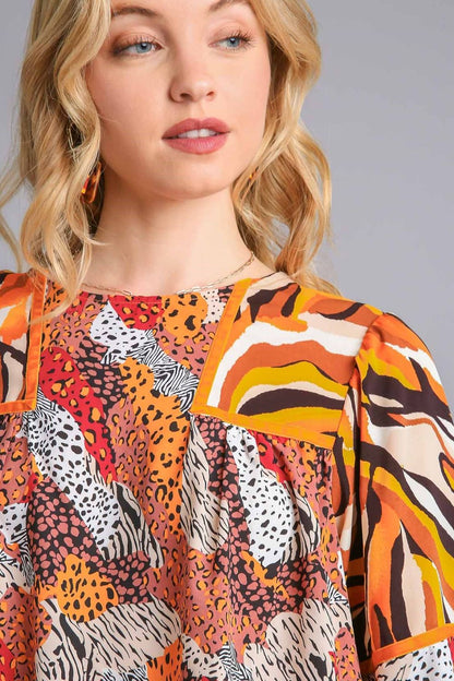 Stylish mixed print blouse with a classic round neckline and flouncy sleeves, perfect for a chic and trendy look.