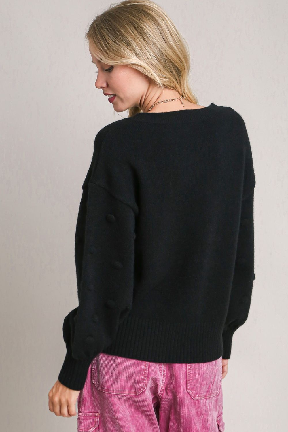 Cozy knit sweater with a playful pom pom heart design and a classic round neckline, perfect for a fun and stylish winter look.