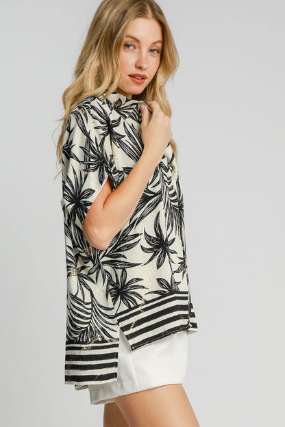 Vibrant tropical print button-down shirt with a high-low hem and side slits, perfect for a relaxed and stylish vacation look.