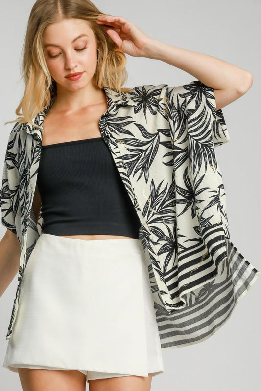 Vibrant tropical print button-down shirt with a high-low hem and side slits, perfect for a relaxed and stylish vacation look.