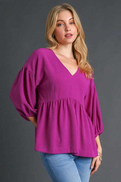 Feminine babydoll blouse with a V-neckline and puffed 3/4 sleeves, perfect for a flowy and elegant look.