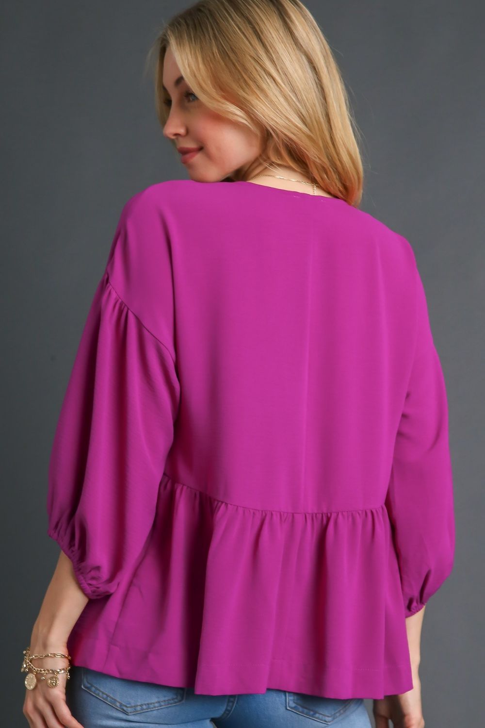 Feminine babydoll blouse with a V-neckline and puffed 3/4 sleeves, perfect for a flowy and elegant look.