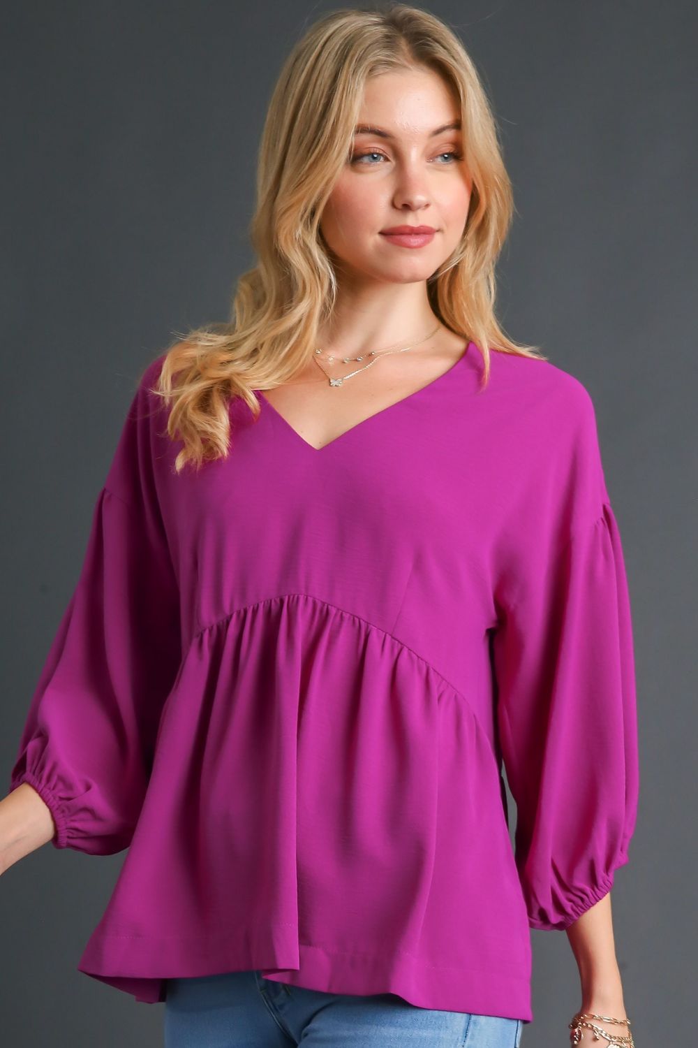 Feminine babydoll blouse with a V-neckline and puffed 3/4 sleeves, perfect for a flowy and elegant look.