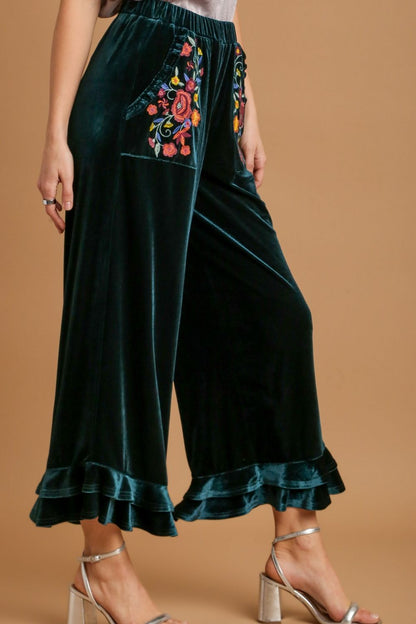 Elegant wide fit velvet pants with ruffle details and embroidered pockets, perfect for a chic and sophisticated look.