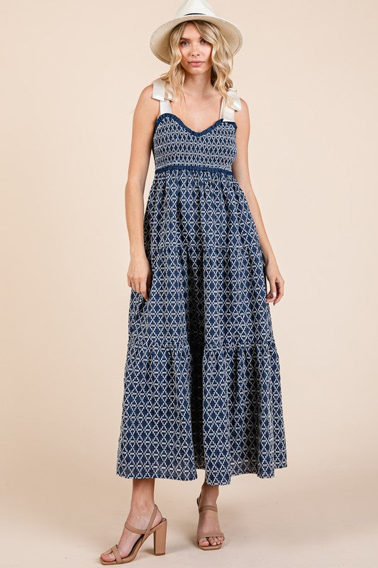 Elegant geometric embroidered smocked tie shoulder midi dress with a flattering silhouette and intricate detailing.