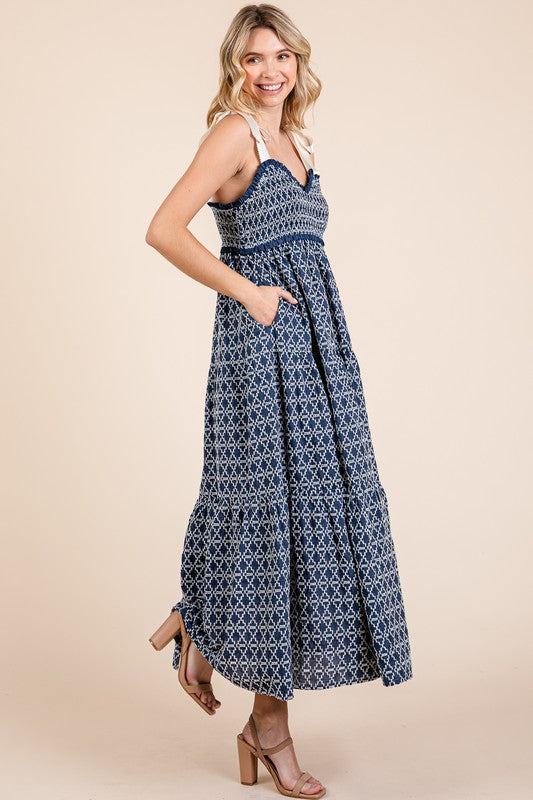 Elegant geometric embroidered smocked tie shoulder midi dress with a flattering silhouette and intricate detailing.