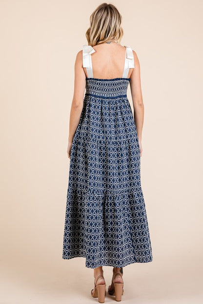 Elegant geometric embroidered smocked tie shoulder midi dress with a flattering silhouette and intricate detailing.