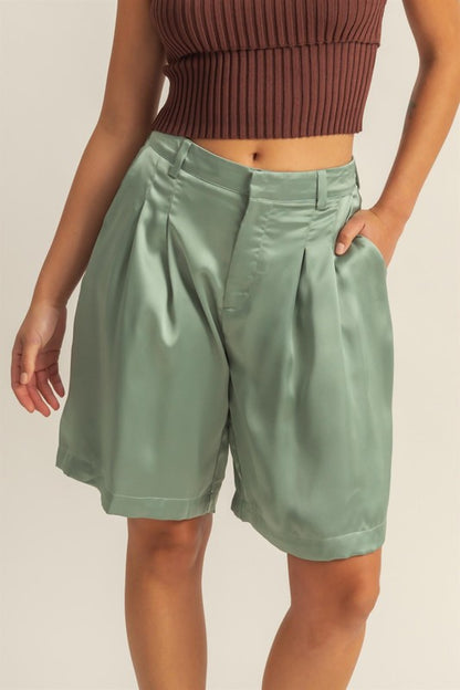 High-waist pleated satin shorts with an elegant finish, featuring a sleek design and functional pockets.