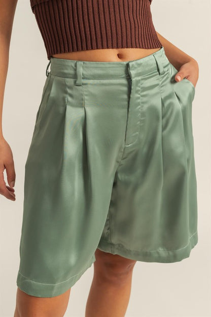 High-waist pleated satin shorts with an elegant finish, featuring a sleek design and functional pockets.