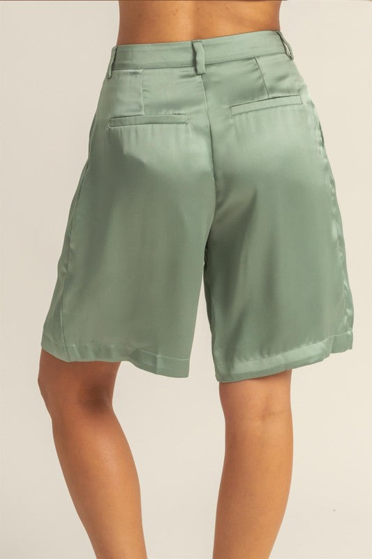 High-waist pleated satin shorts with an elegant finish, featuring a sleek design and functional pockets.