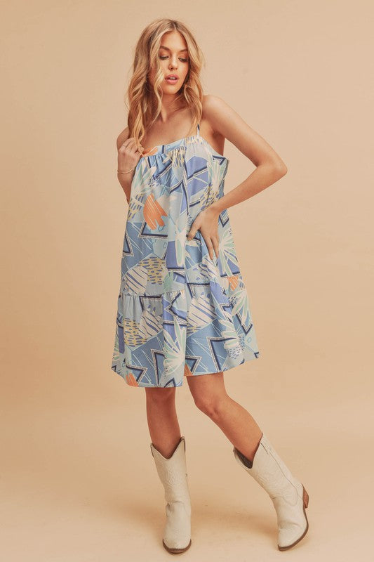 Flirty printed square neck mini cami dress with ruffled hem, perfect for casual and summer occasions.