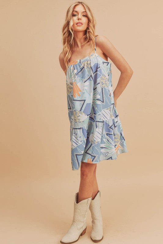 Flirty printed square neck mini cami dress with ruffled hem, perfect for casual and summer occasions.