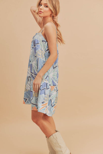 Flirty printed square neck mini cami dress with ruffled hem, perfect for casual and summer occasions.