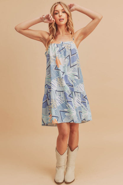 Flirty printed square neck mini cami dress with ruffled hem, perfect for casual and summer occasions.