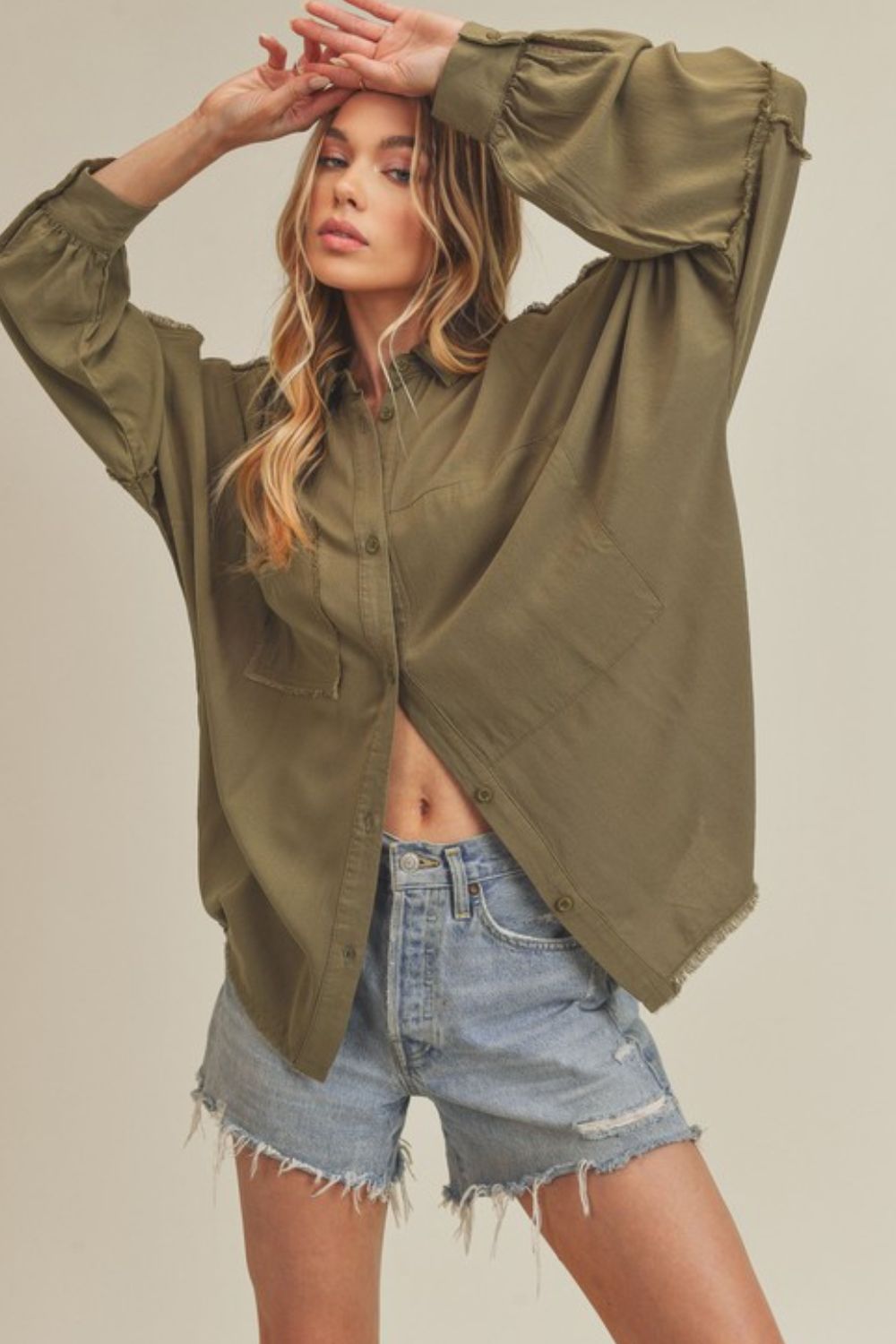 Trendy raw edge exposed seam collared long sleeve shirt with a high-low hem for a modern and edgy look.