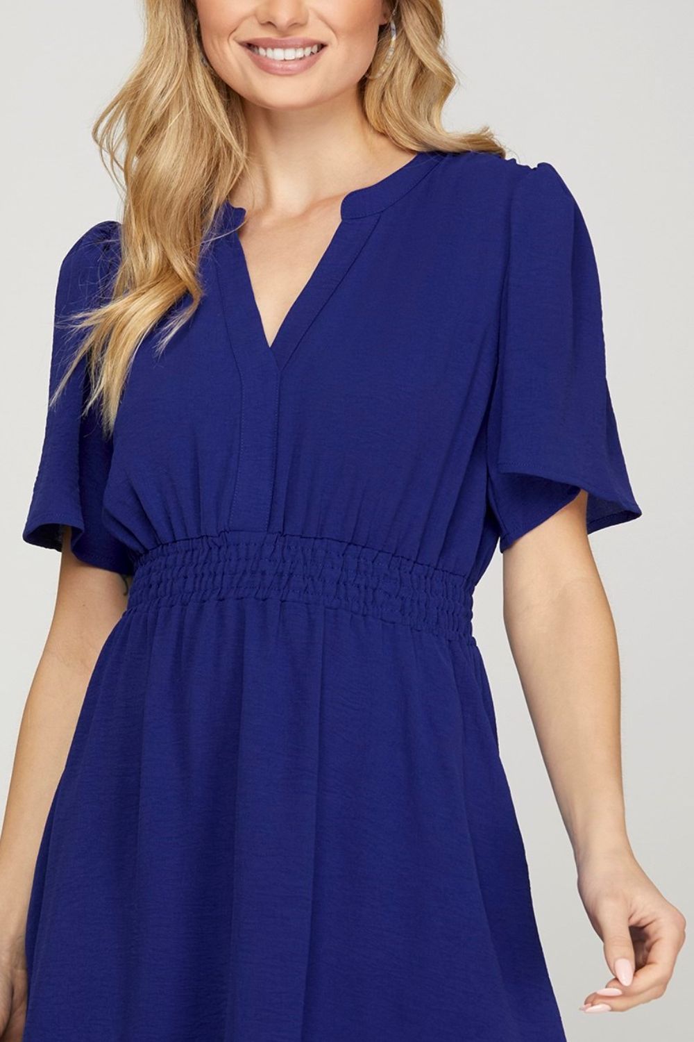 Chic ruffled hem notched flutter sleeve mini dress with a flattering smocked waist and romantic design.