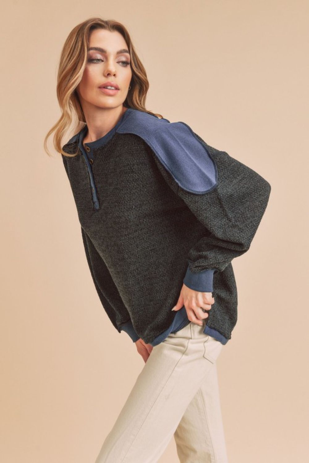 Trendy sweatshirt with side slits, button details, and contrast shoulder design, perfect for casual or athleisure wear.